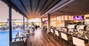 Spacious modern restaurant interior with a poolside view, featuring elegant furniture and contemporary design.