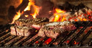 Succulent steaks grilling over hot coals and flames for a mouthwatering cookout.